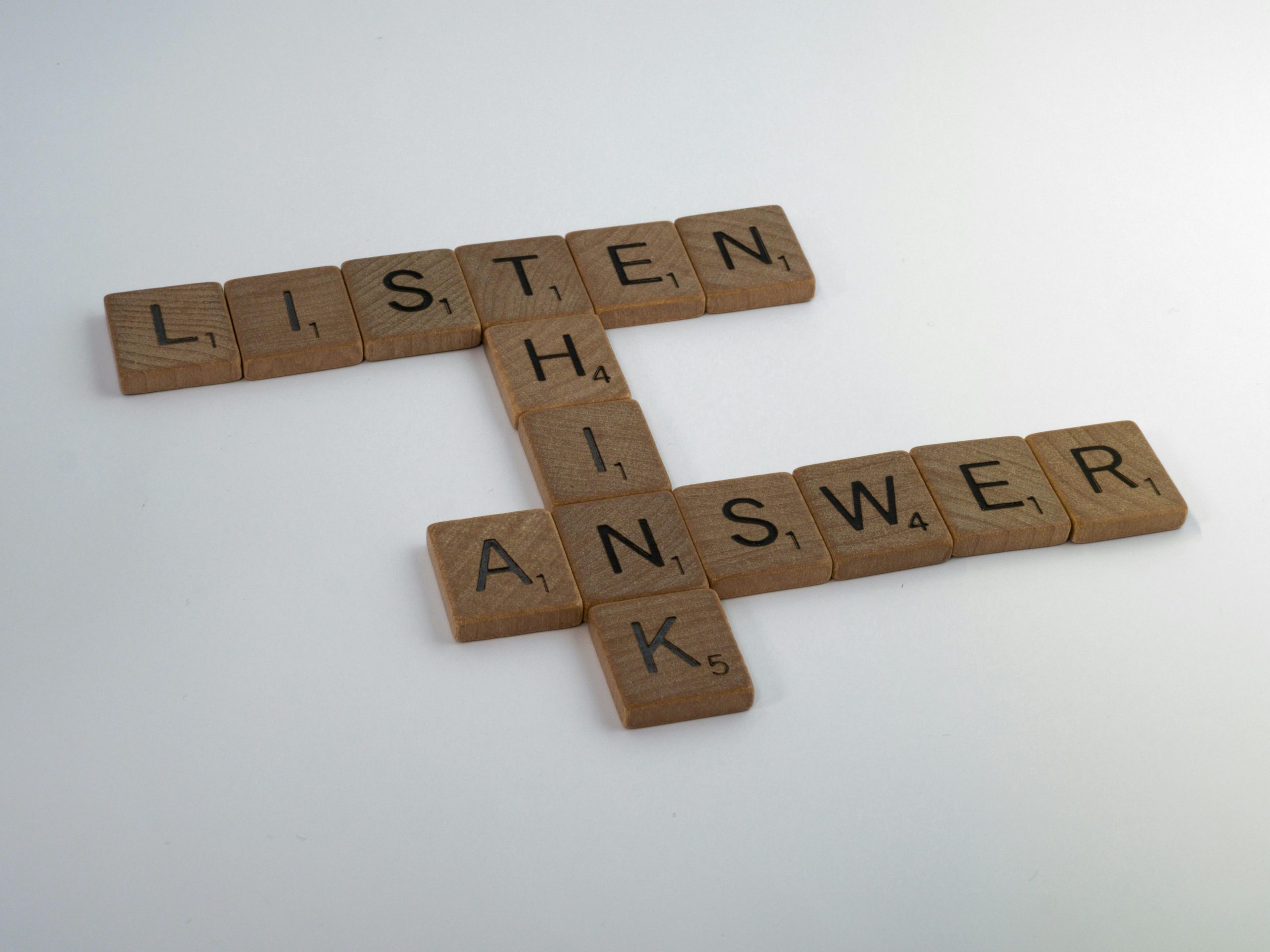 Scrabble tiles on a white surface spell out "LISTEN" horizontally and "THINK" and "ANSWER" vertically, crossing at the 'N' and 'I' respectively.